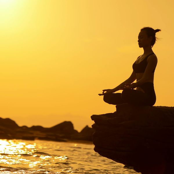 Silhouette of a person in a warrior yoga pose against a beautiful sunset.